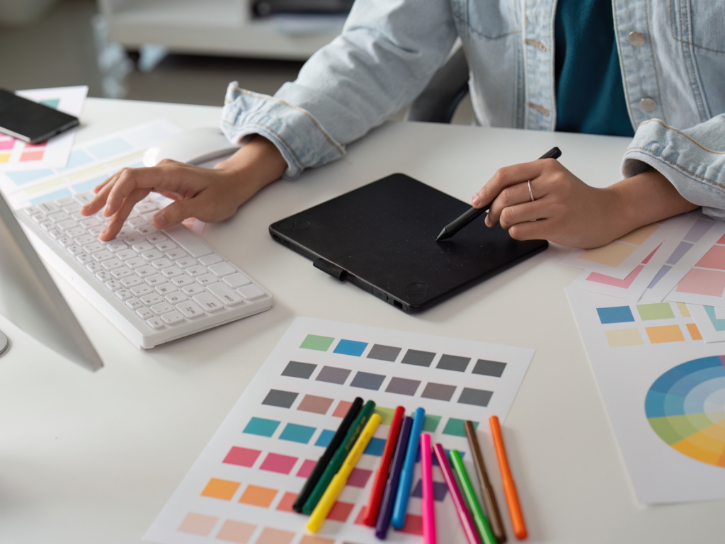 Woman designing with a color palette, tablet, and desktop computer