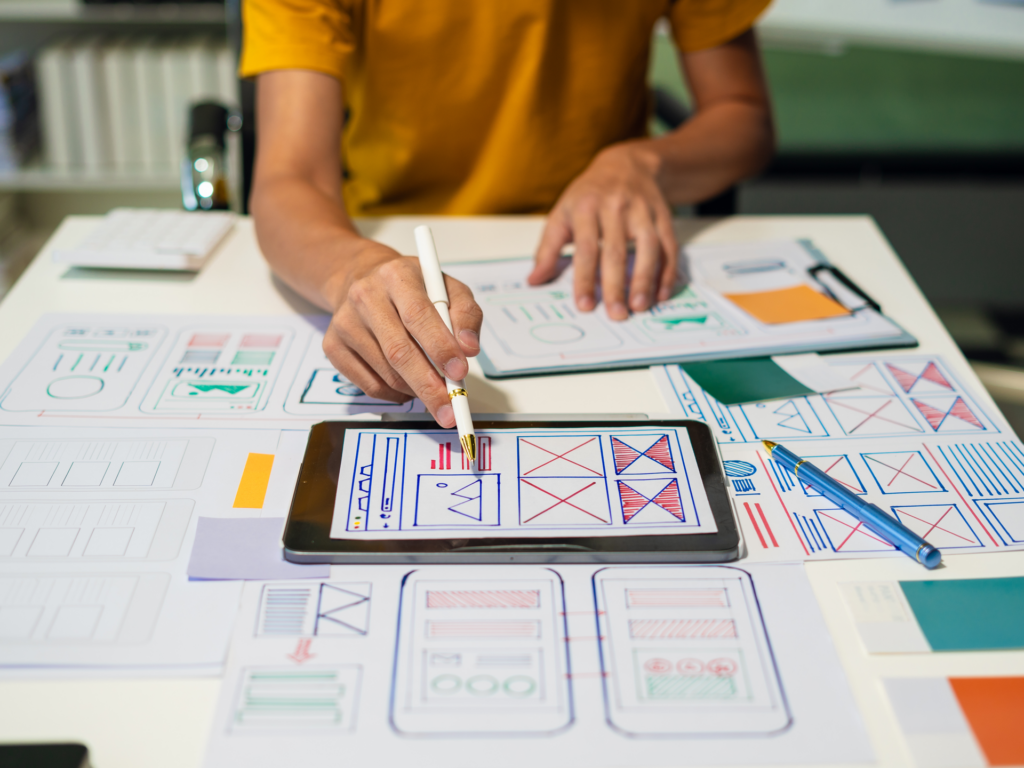Woman designing at her desk with a tablet and design papers surrounding
